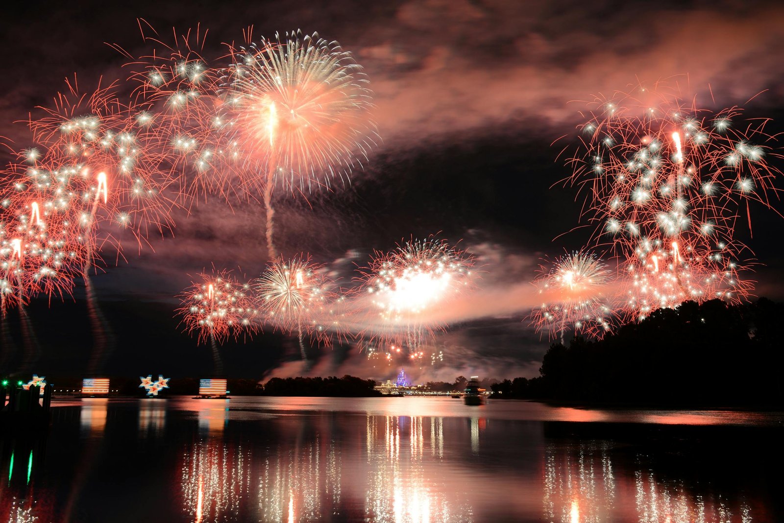 Dazzling fireworks light up the night sky over Lake Buena Vista, FL, creating a stunning reflection on the water.