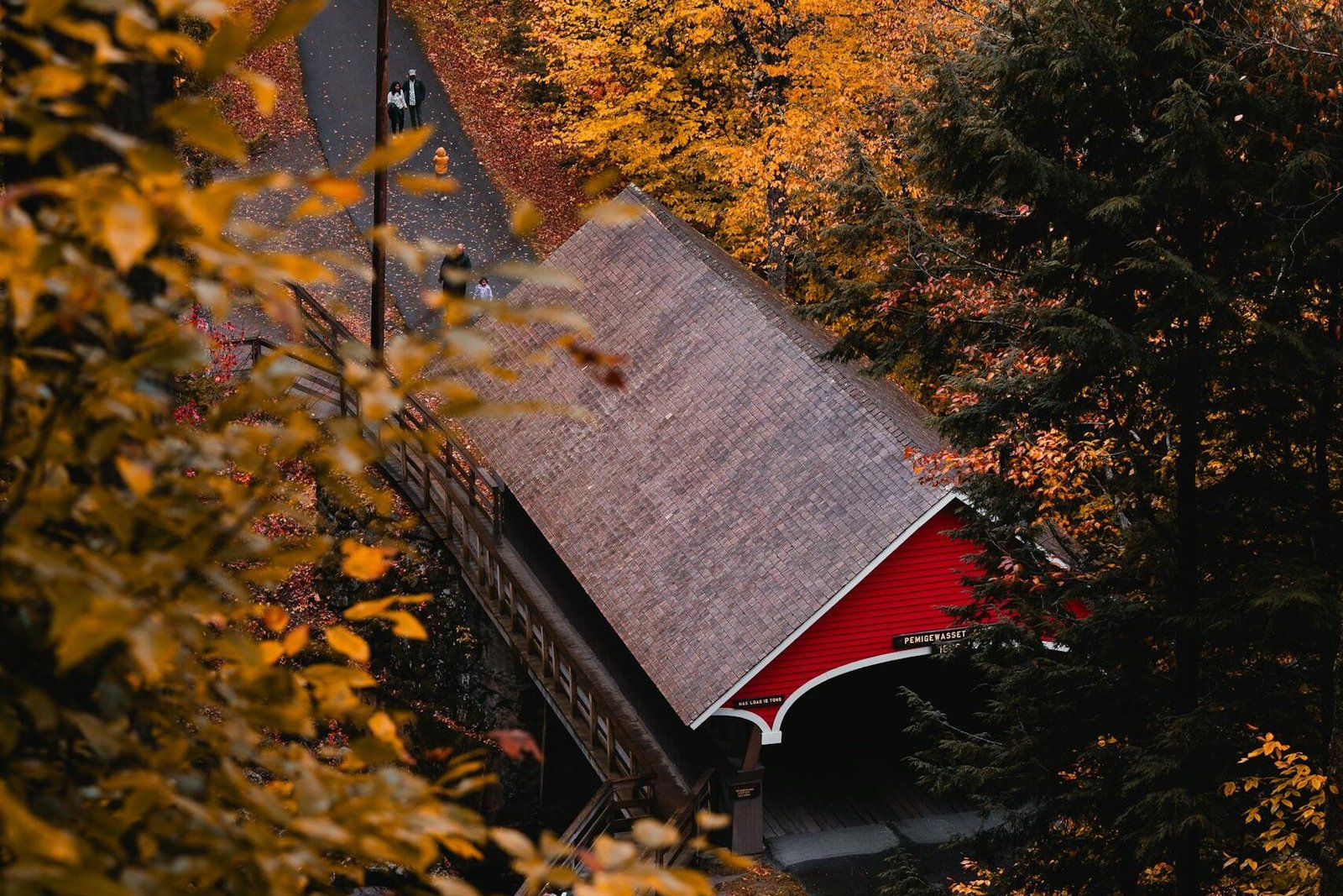 A beautiful autumn scene featuring a red covered bridge surrounded by vibrant fall foliage in Lincoln, New Hampshire.