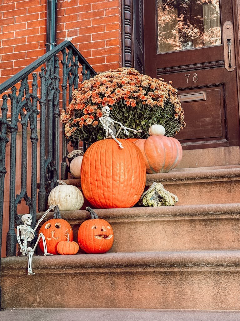 Festive fall decorations of pumpkins and skeletons on brownstone steps in Brooklyn
