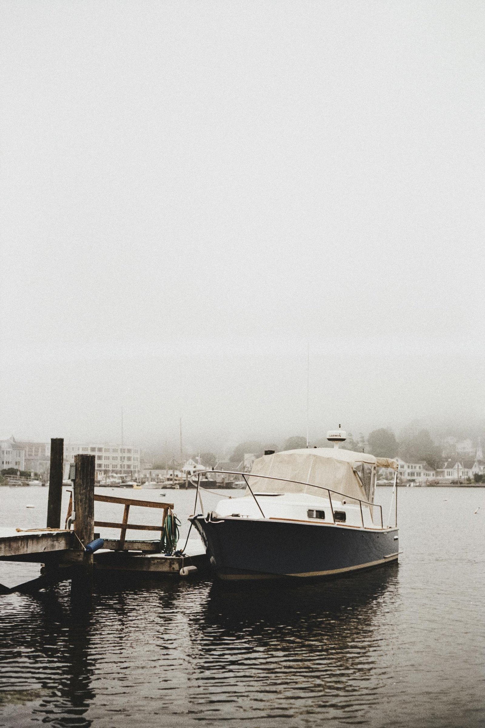 A serene foggy scene at Mystic Seaport featuring a boat docked in the harbor.
